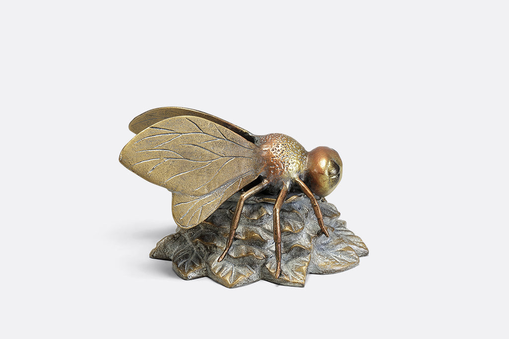A statue of a bee landing on a flower.