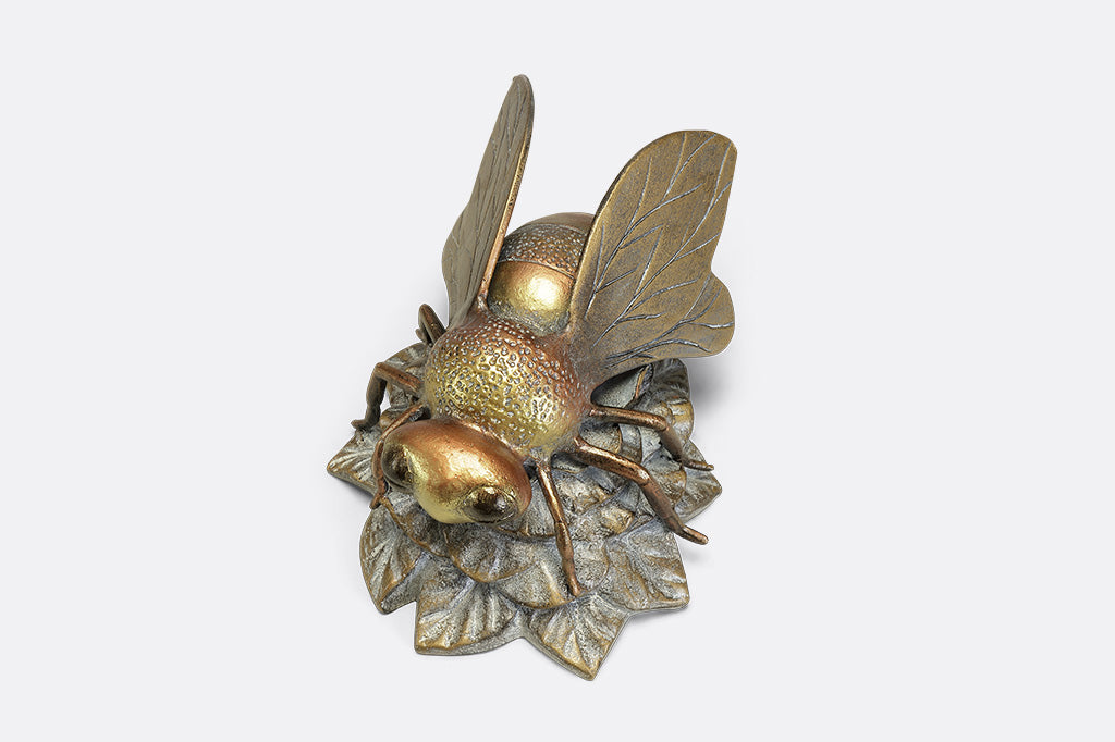A statue of a bee landing on a flower.
