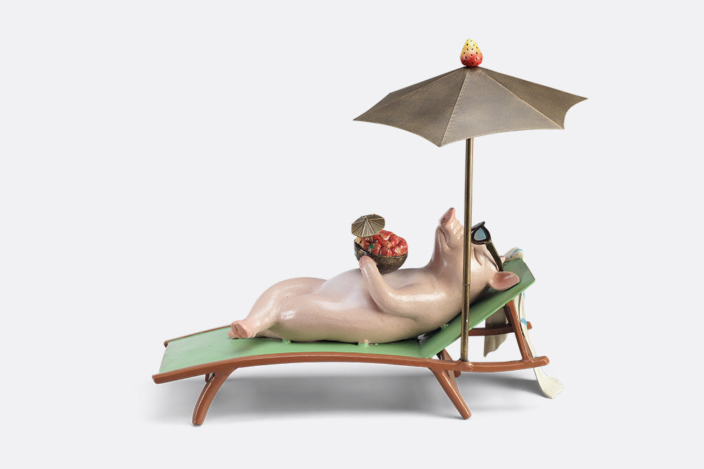 Decorative figurine of a pig on a beach chair with an umbrella