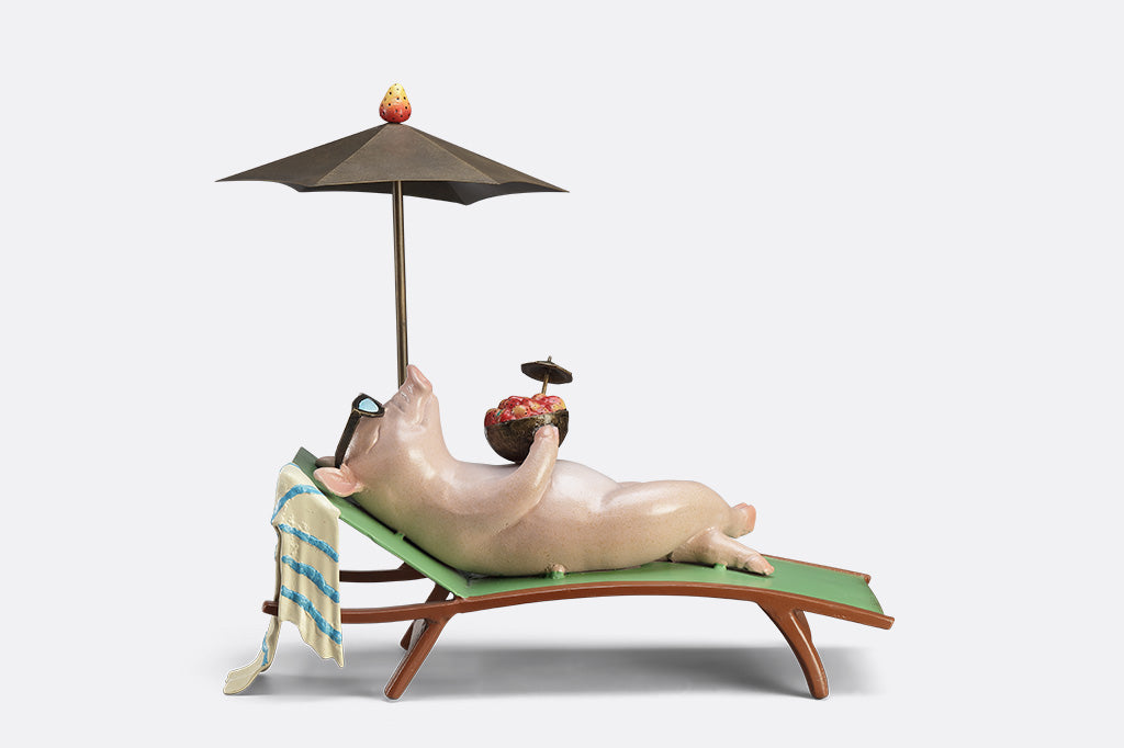 Decorative figurine of a pig on a beach chair with an umbrella