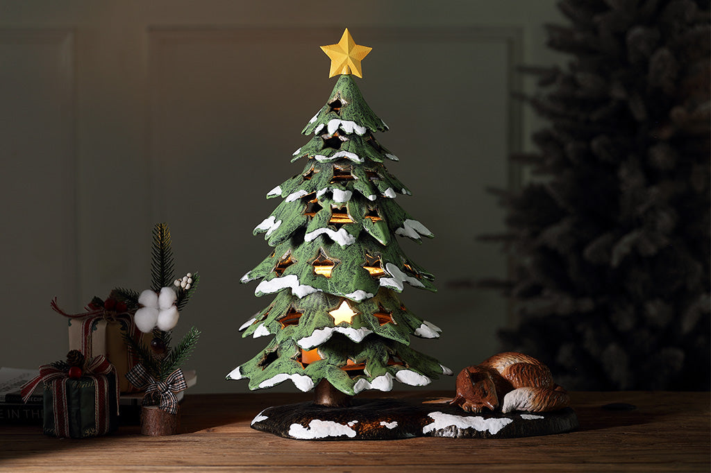 Decorative Christmas tree figurine with a star on top and a fox at its base.