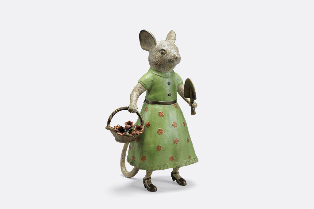 A mouse in a green dress holding a shovel and a basket of flowers.