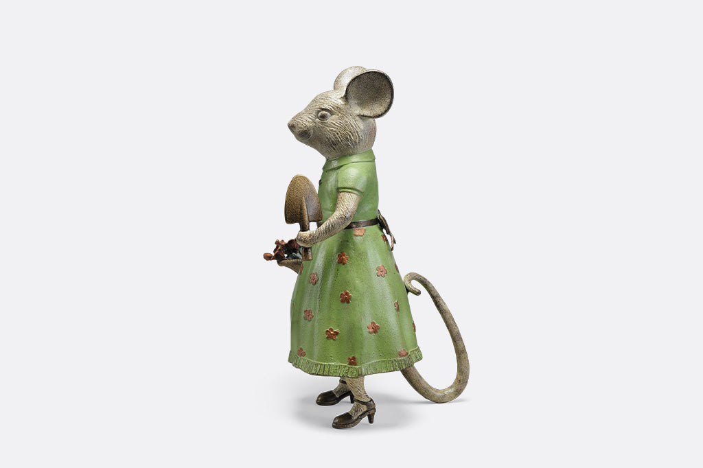 A mouse in a green dress holding a shovel and a basket of flowers.