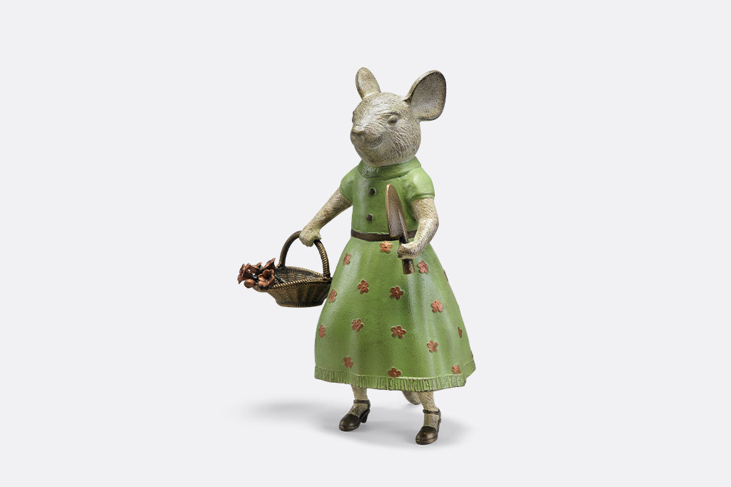 A mouse in a green dress holding a shovel and a basket of flowers.