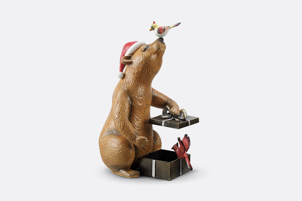 A heartwarming sculpture of a bear opening presents with his bird friends.