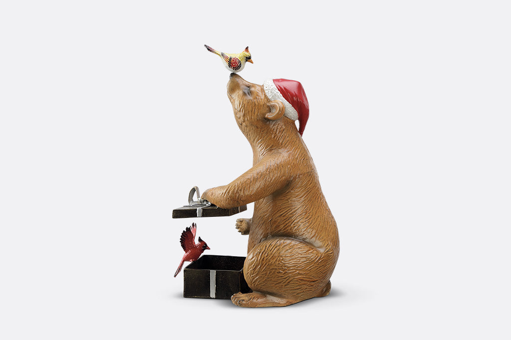 A heartwarming sculpture of a bear opening presents with his bird friends.
