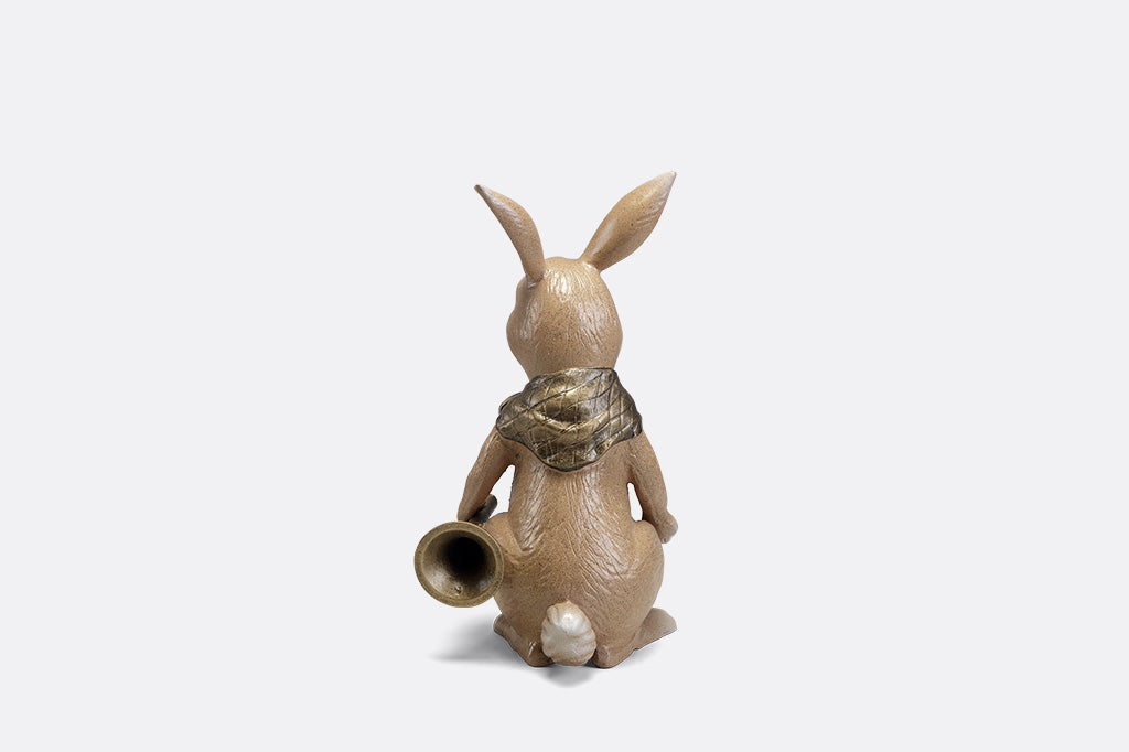 A sculpture of a bunny with a scarf and horn.