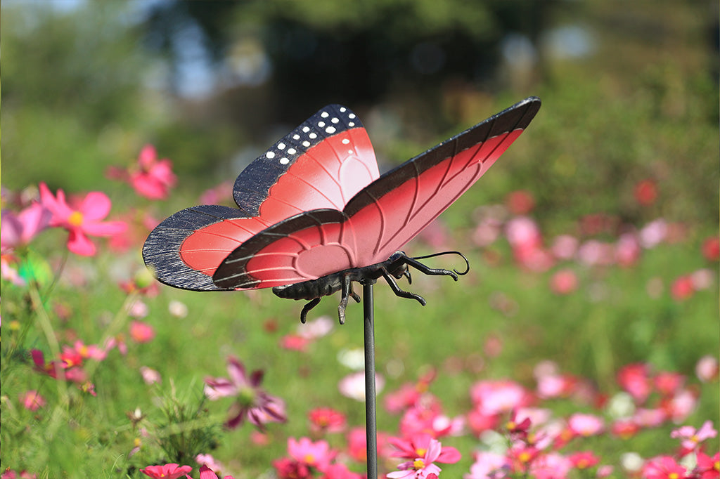 A garden stake sculpture of a pink, red, and black butterfly.