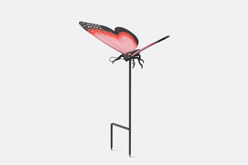 A garden stake sculpture of a pink, red, and black butterfly.