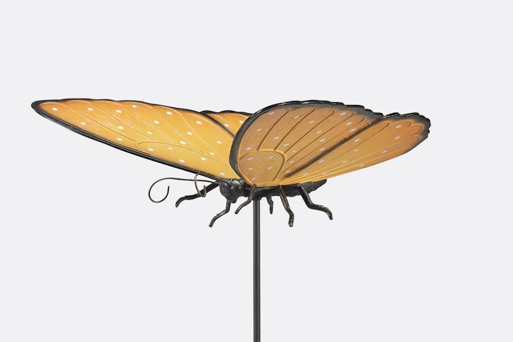 Butterfly-shaped garden stake with orange wings and black body on a white background