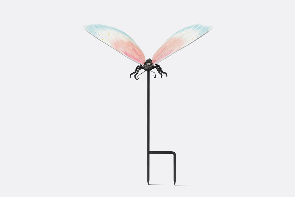 A garden stake sculpture of a butterfly with hues of light blue, white, and pink with yellow details.