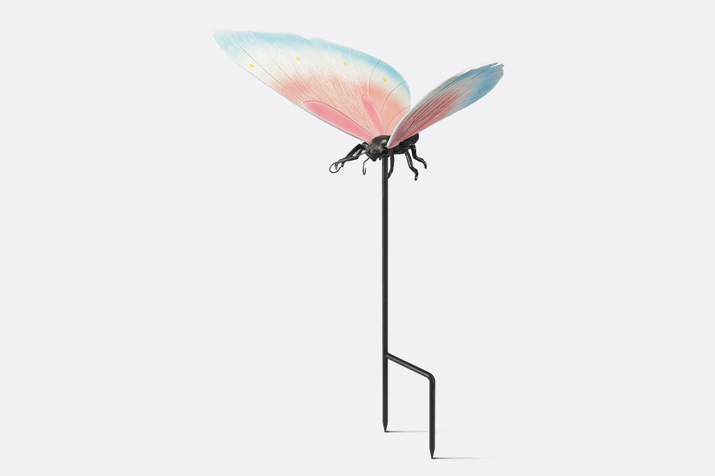 A garden stake sculpture of a butterfly with hues of light blue, white, and pink with yellow details.