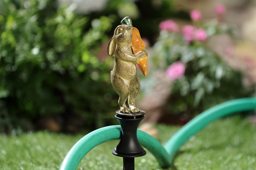 A hose guard of a bunny rabbit holding a carrot.