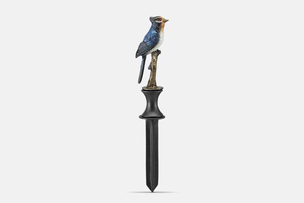 A hose guard sculpture of a Blue Bird sitting upon a twig.