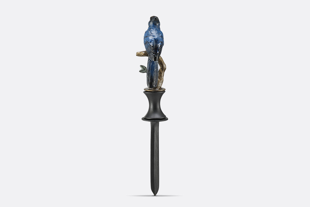A hose guard sculpture of a Blue Bird sitting upon a twig.