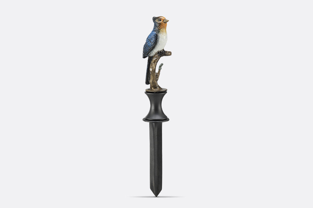 A hose guard sculpture of a Blue Bird sitting upon a twig.