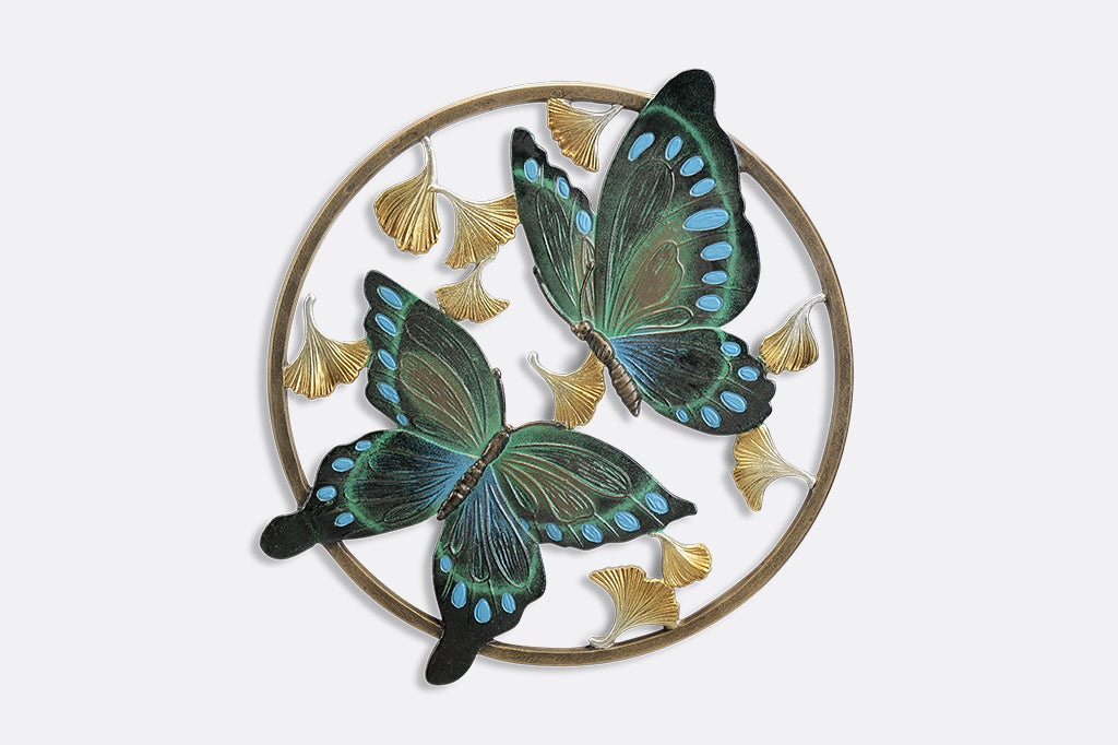 Circular wall art piece with ginkgo flowers and two blue and green butterflies.