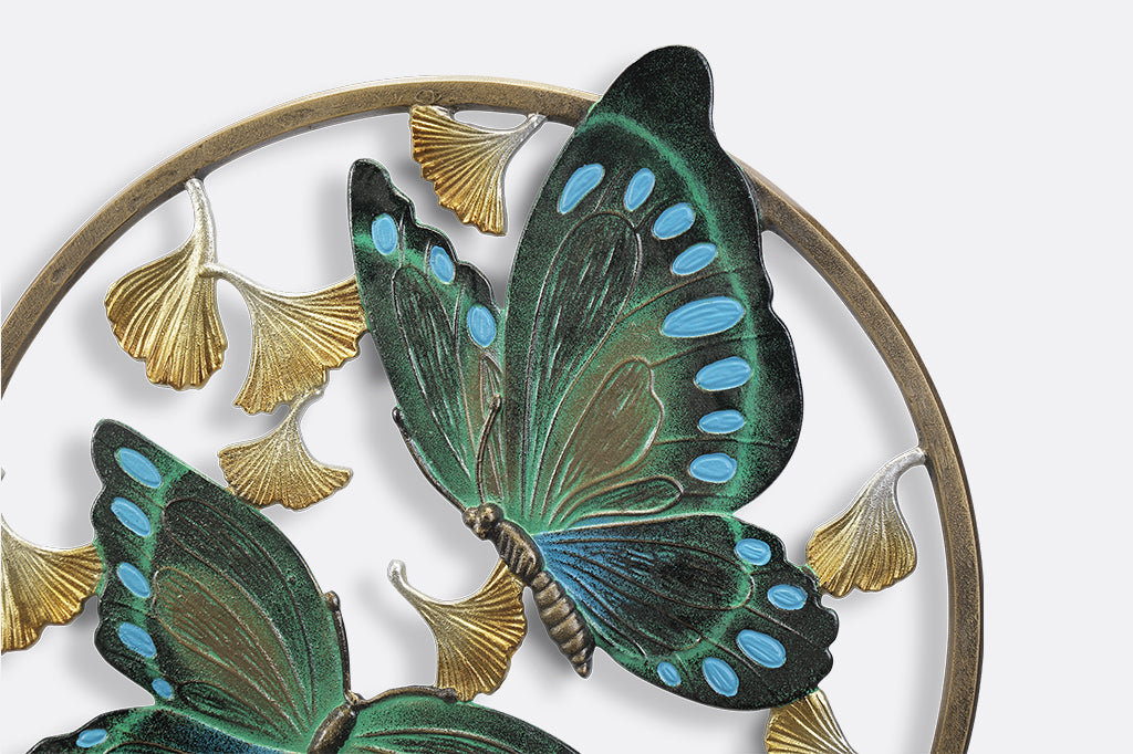 Circular wall art piece with ginkgo flowers and two blue and green butterflies.