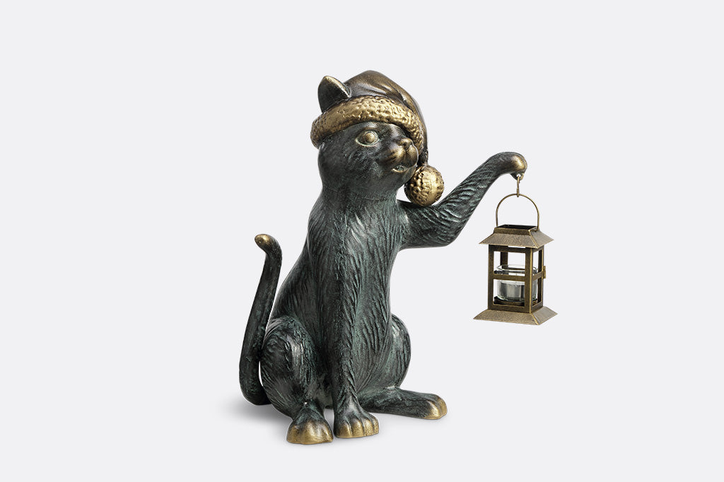 Cat figurine wearing a hat and holding a lantern on a white background