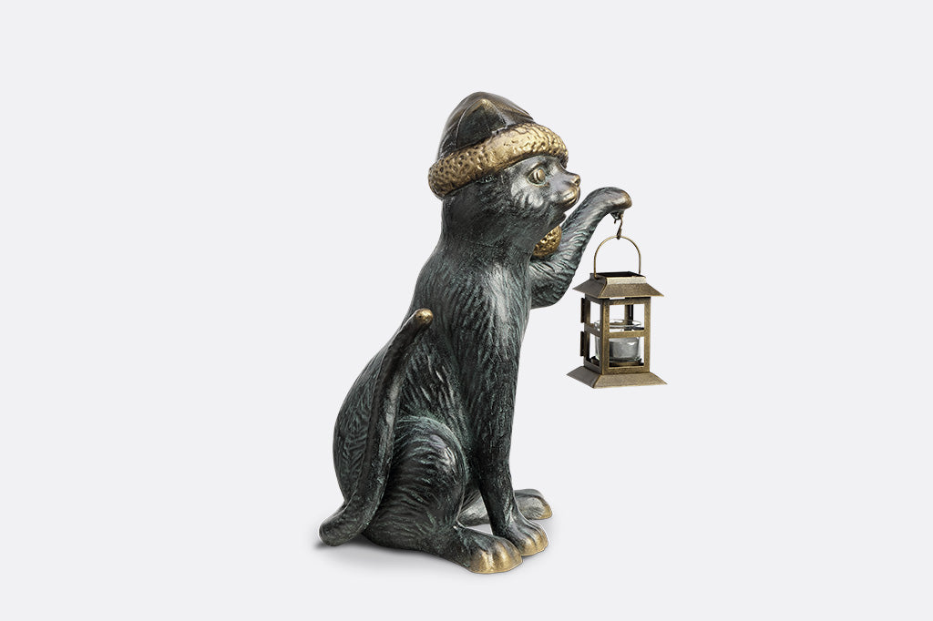Cat figurine wearing a hat and holding a lantern on a white background
