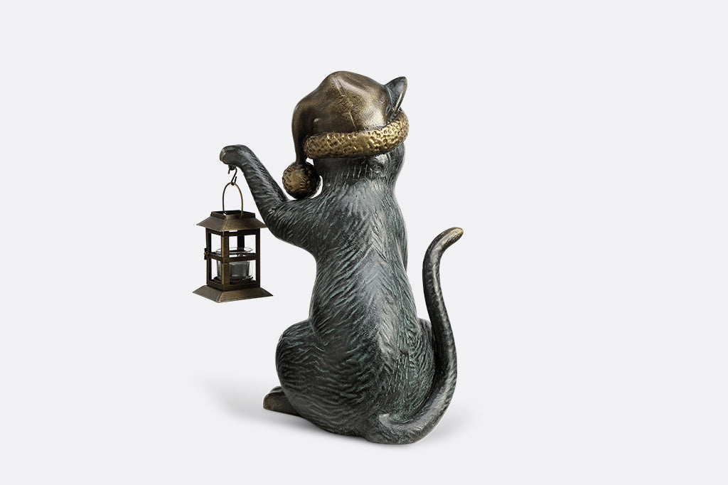 Cat figurine wearing a hat and holding a lantern on a white background