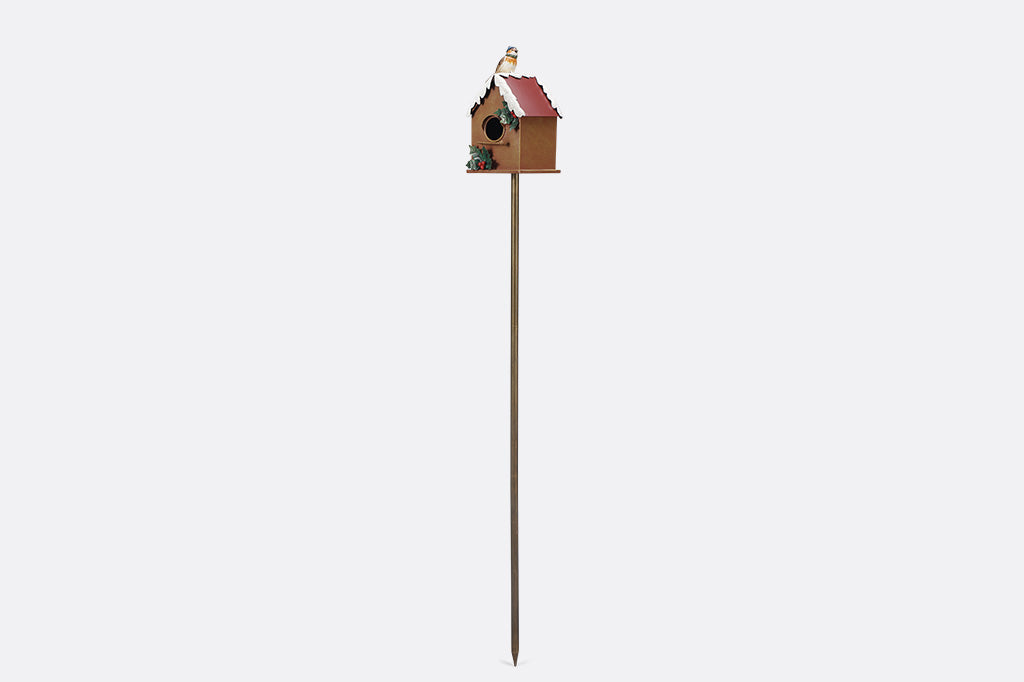 A holiday themed birdhouse with a bird wearing a knitted cap and scarf.