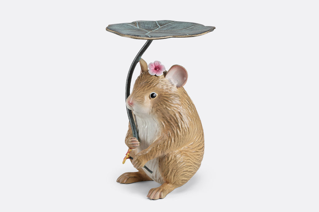 A sculpture of a hamster holding a leaf and flower