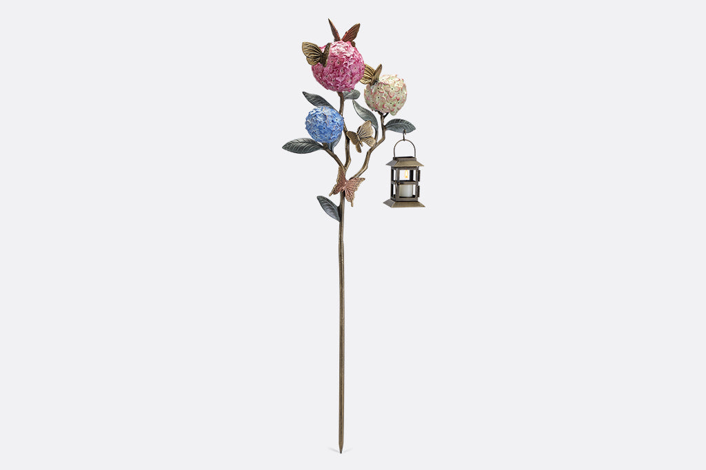 A garden stake lantern of 3 hydrangea flowers with a group of butterflies.