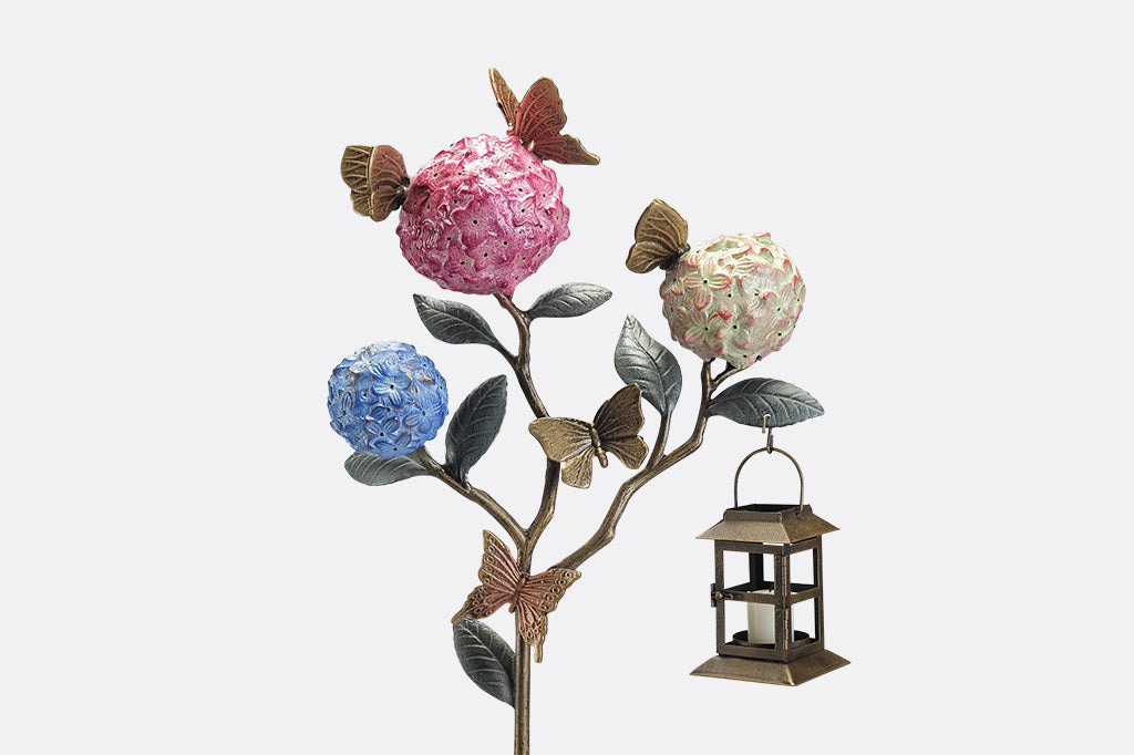 A garden stake lantern of 3 hydrangea flowers with a group of butterflies.