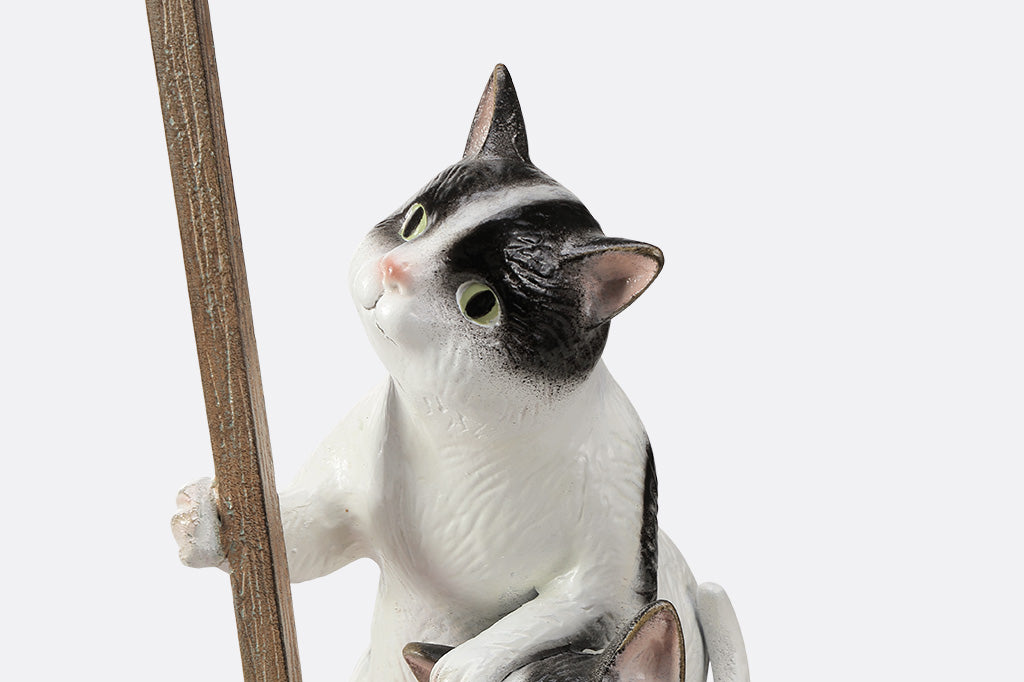 A garden sculpture of two cats holding a sign that says "love grows here" with a bird sitting on the sign and a pair of flowers at the bottom.