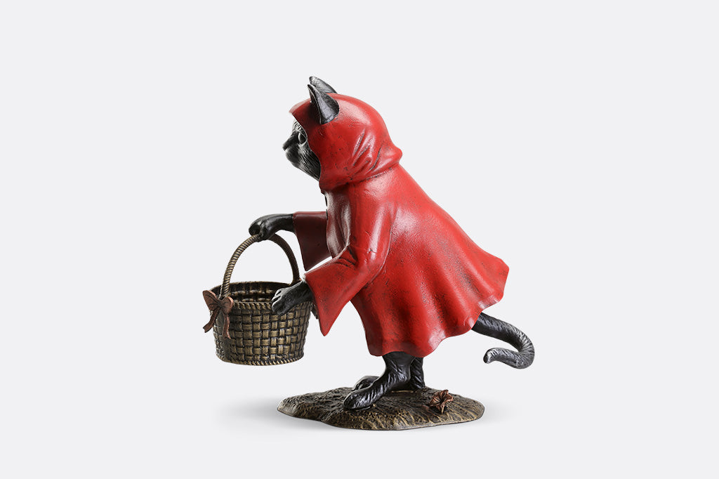 Statue of a creature in a red hood holding a basket on a white background