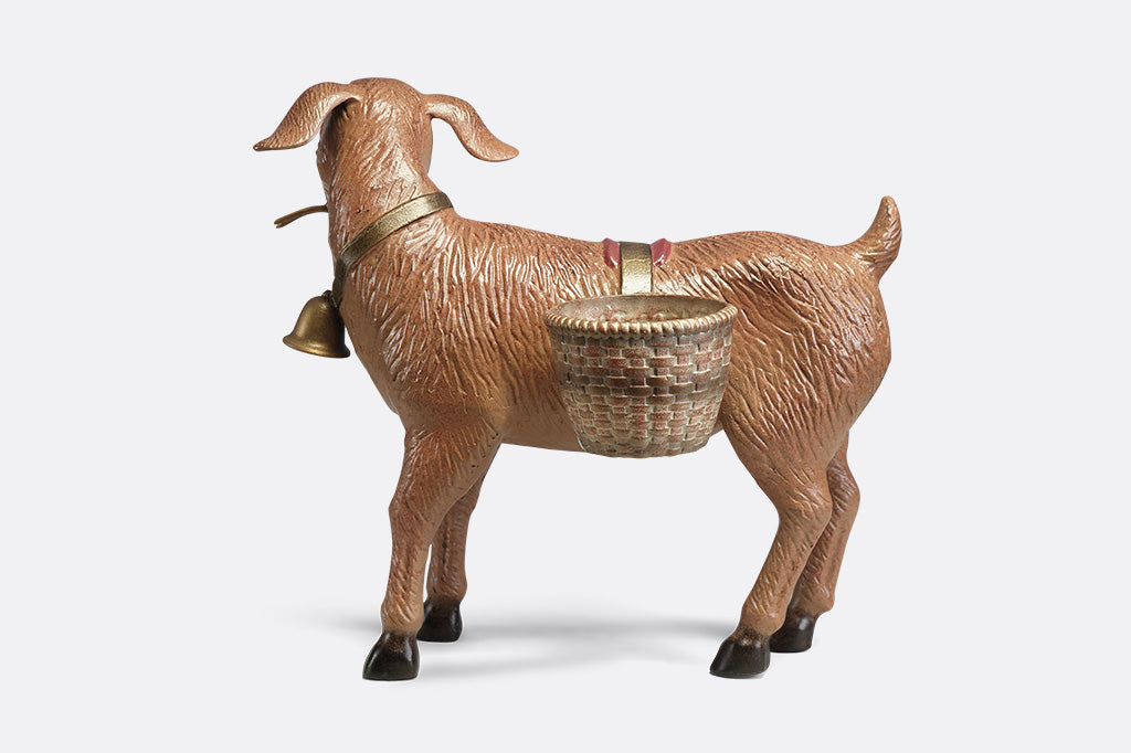 A planter sculpture of a goat with a bell carrying two baskets at his side.