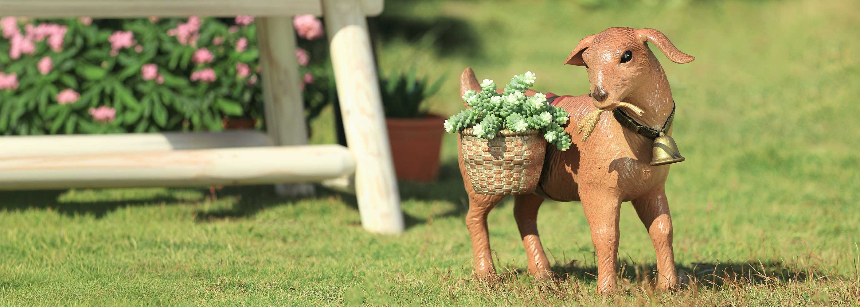 Decorative metal goat with a basket of flowers on a grassy lawn.