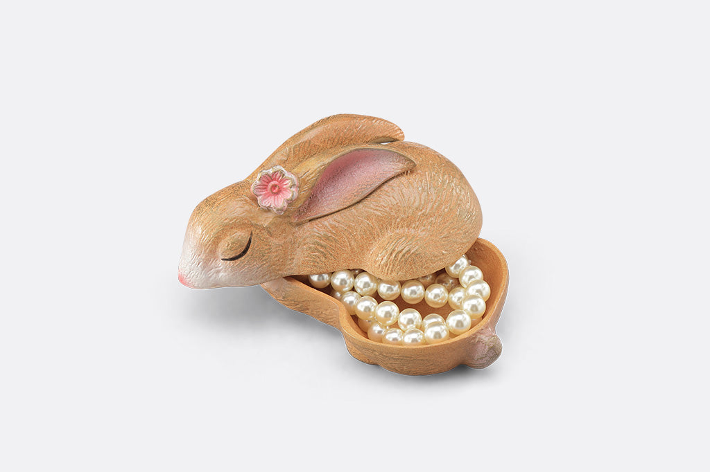 A sleeping bunny shaped keepsake box with pearls inside