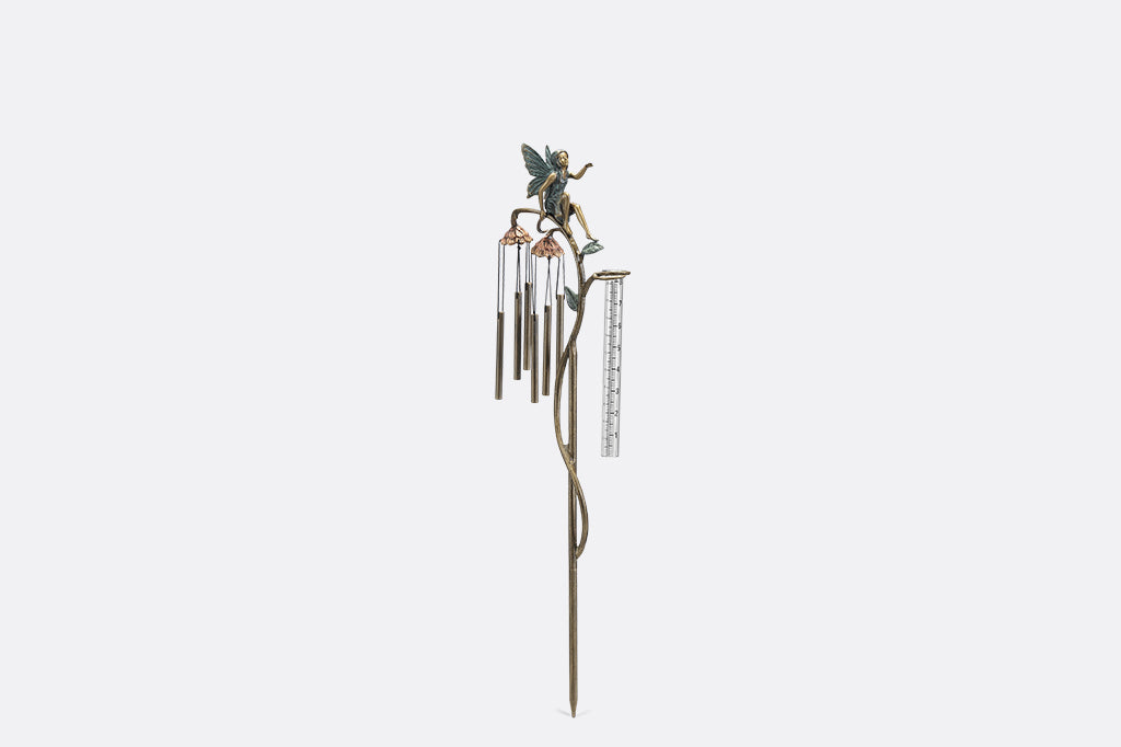 A staked raincatcher and windchime of a fairy sitting on flowers.