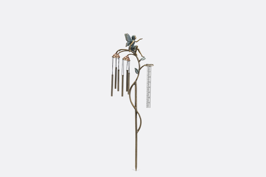 A staked raincatcher and windchime of a fairy sitting on flowers.