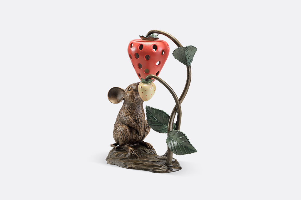A sculpture of a mouse looking up at a strawberry shaped lantern.