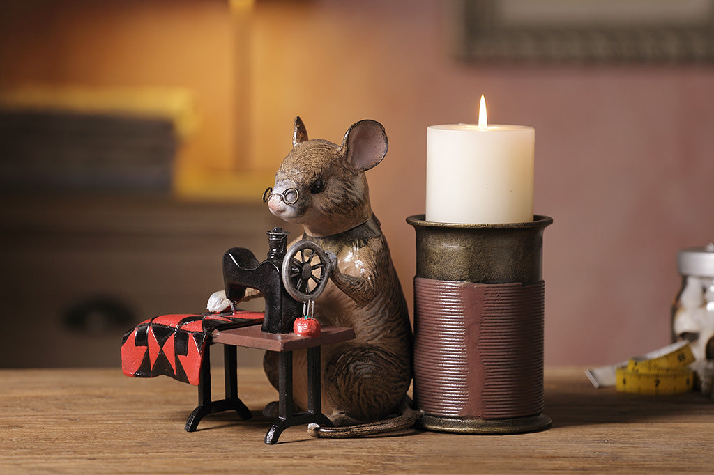 A candleholder of a mouse at a sewing machine stitching fabric.