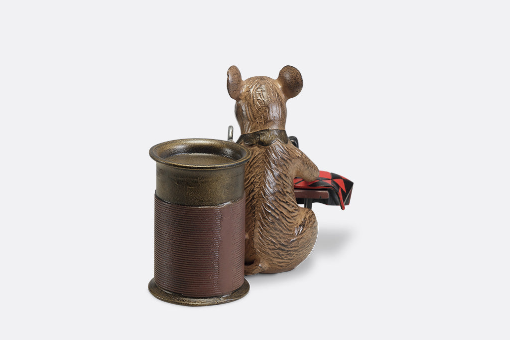 A candleholder of a mouse at a sewing machine stitching fabric.