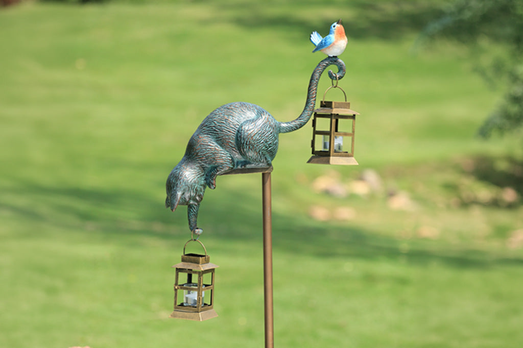 Decorative garden stake with cat and bird design on a grassy background