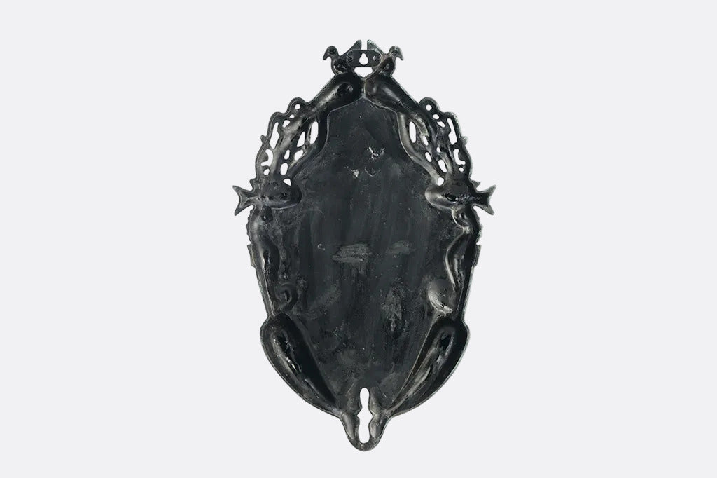Decorative metal wall plaque with intricate designs on a white background, back angle