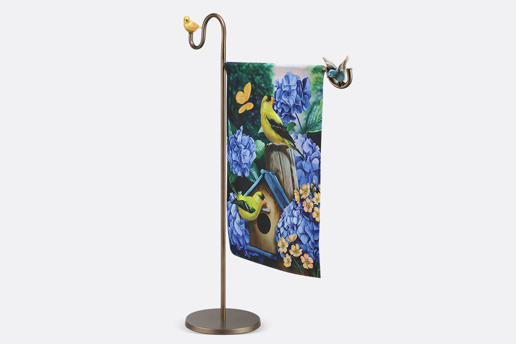 A flag stand with two birds holding a flag with a birdhouse