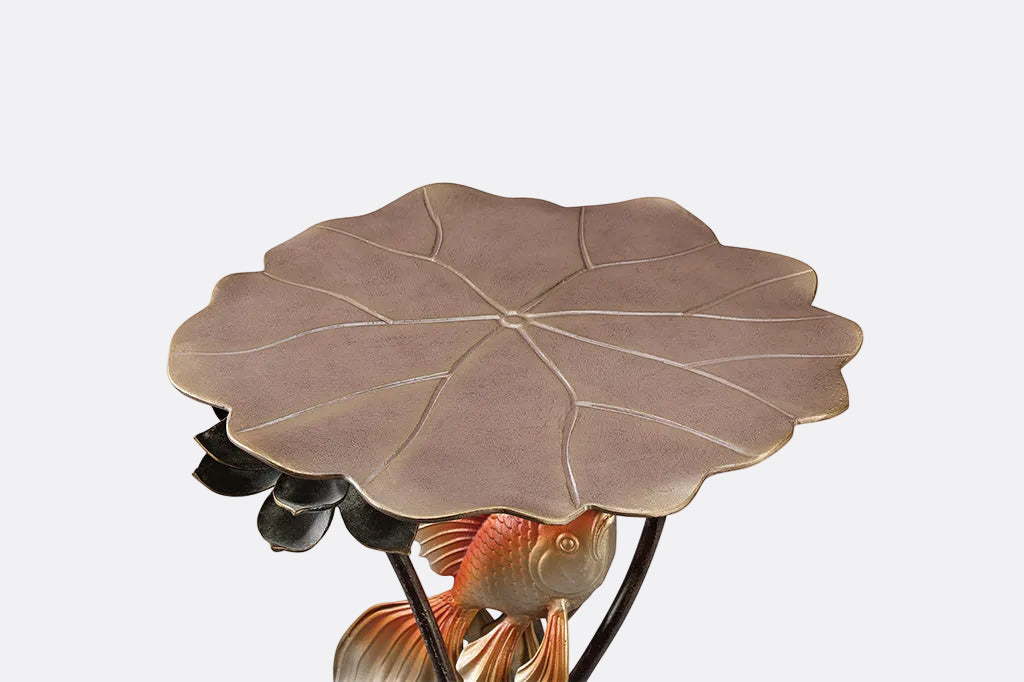 Decorative table with leaf-shaped top and koi fish sculpture on a white background