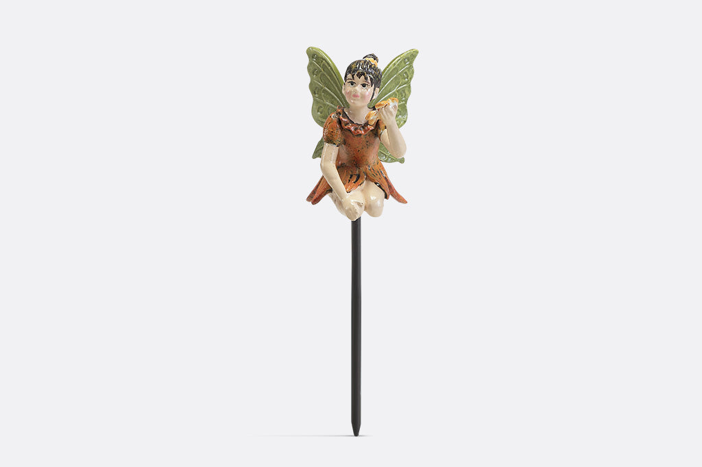 A plant pot stake sculpture of a fairy wearing orange and holding a flower.