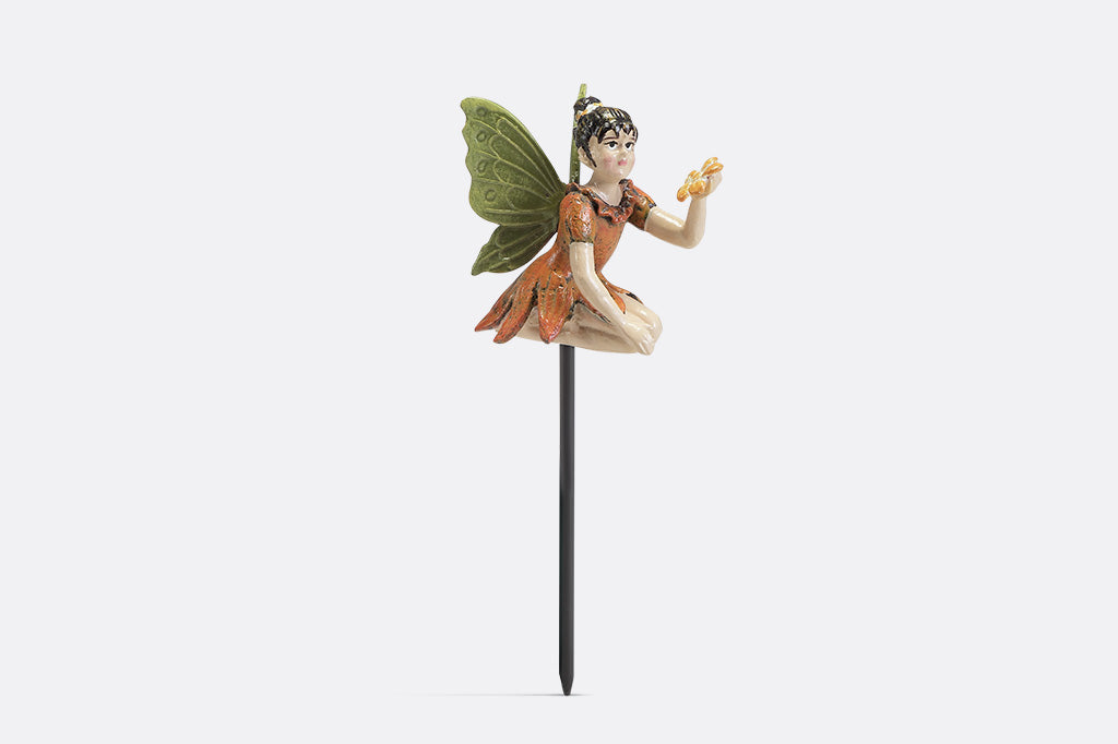 A plant pot stake sculpture of a fairy wearing orange and holding a flower.