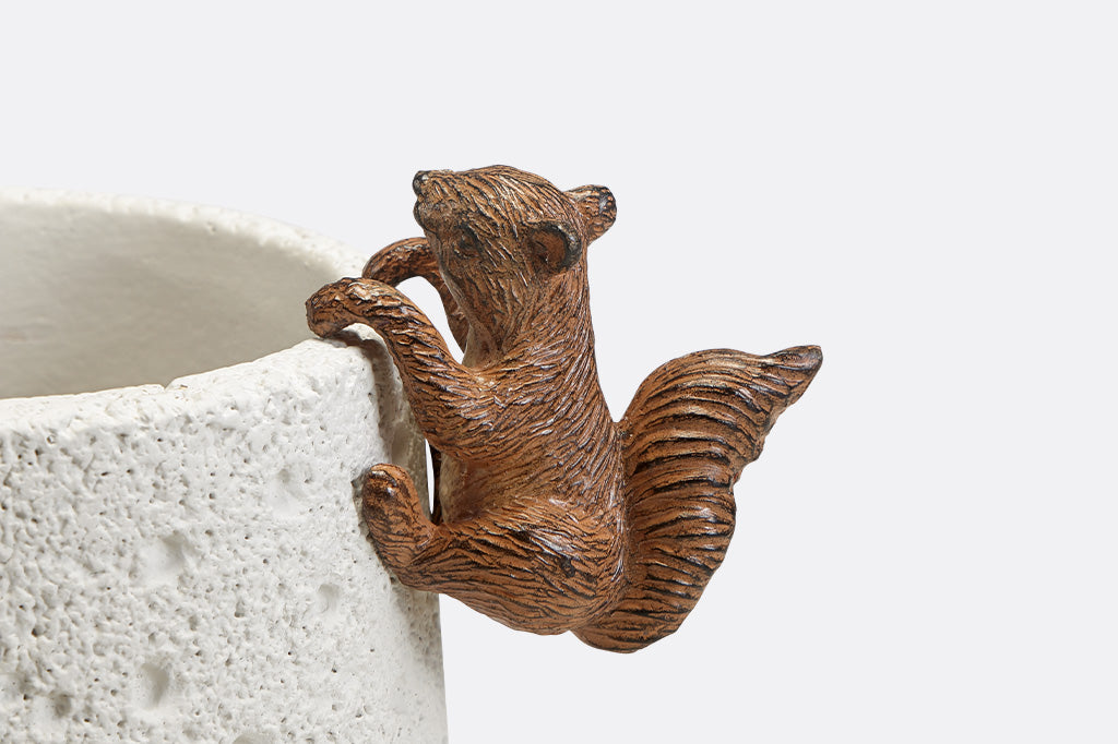 A pot hanging sculpture of a squirrel climbing.