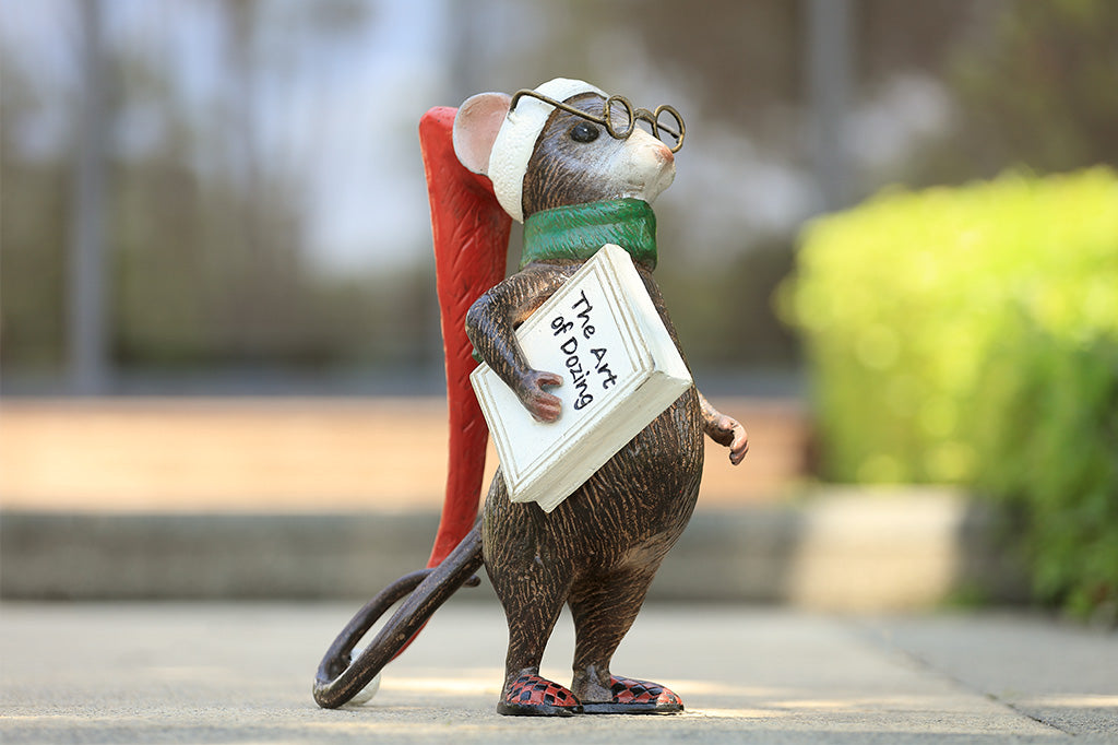 A mouse with glasses, a long night cap, slippers, a green scarf, and a book called "The Art of Dozing."