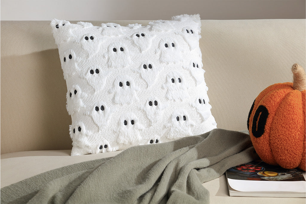 Decorative pillow with black dots on a bed next to a pumpkin and book
