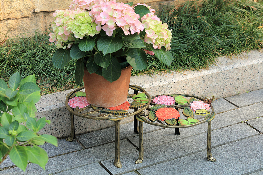 A set of 2 plant stands featuring details of pink hydrangeas, leaves, snails, and butterflies.