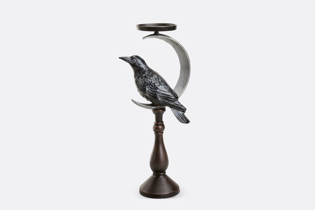 Decorative candle holder with a bird and crescent moon design on a white background